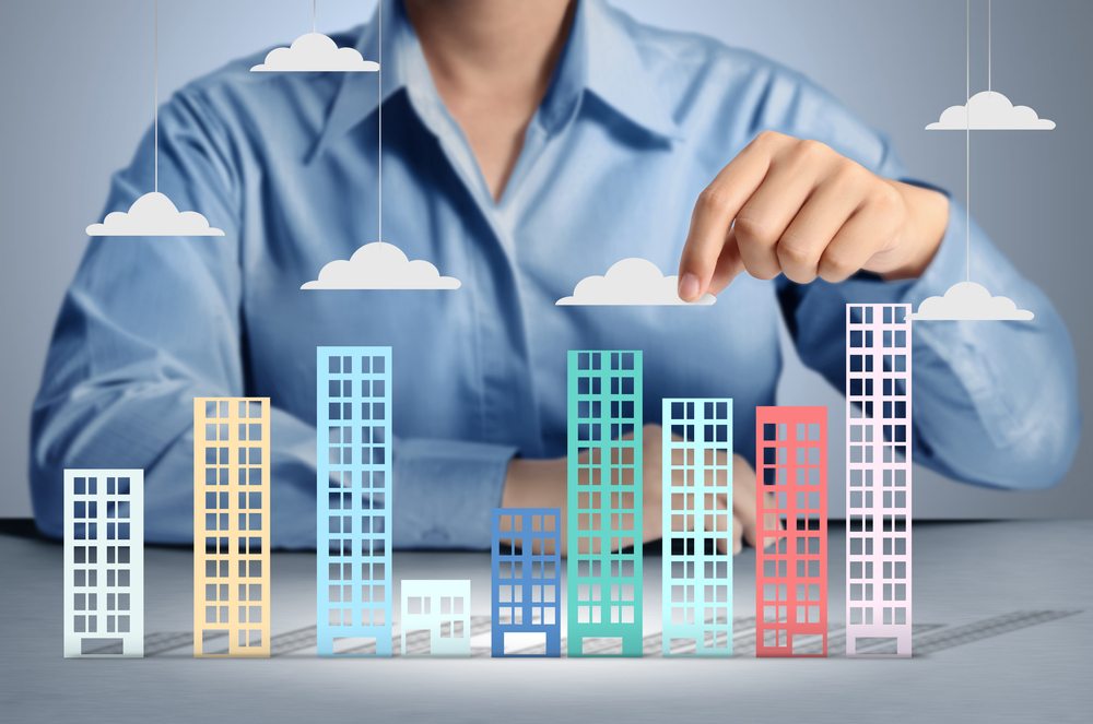 Buttonwood Property Management- a picture of a person in a professional sitting at a table with a 3D diagram of a collection of buildings in front.